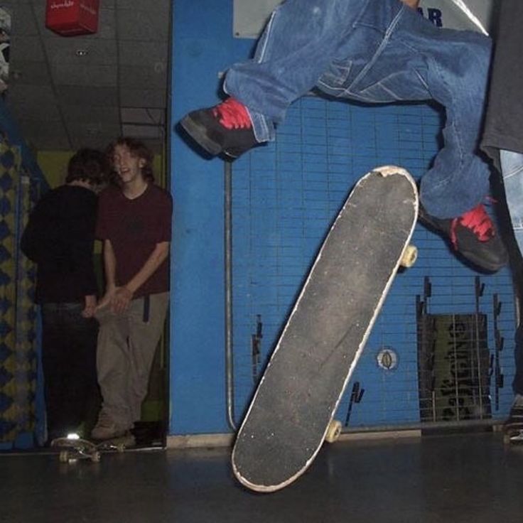 a person jumping in the air on a skateboard with other people standing around watching