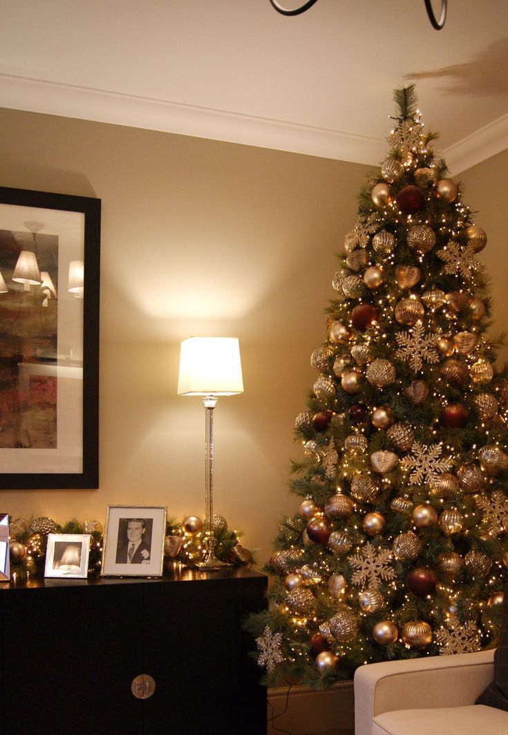 a living room decorated for christmas with a large tree in the corner and pictures on the wall