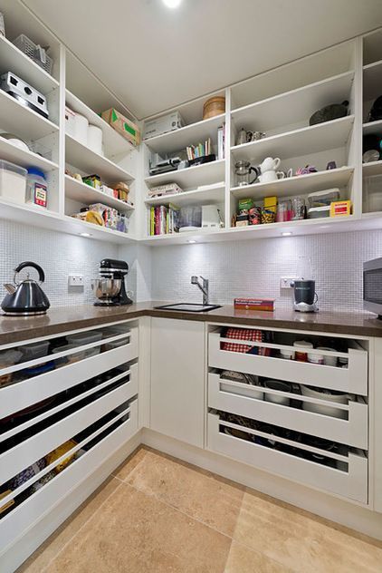 a kitchen with lots of white cabinets and drawers