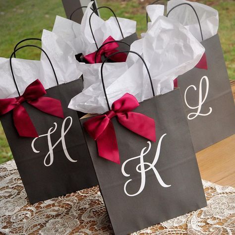 three bags with red bows are sitting on a lace tablecloth, one is black and the other is white