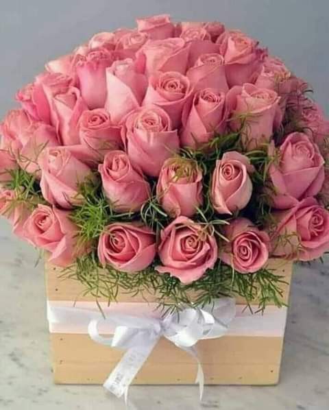 a bouquet of pink roses in a wooden box