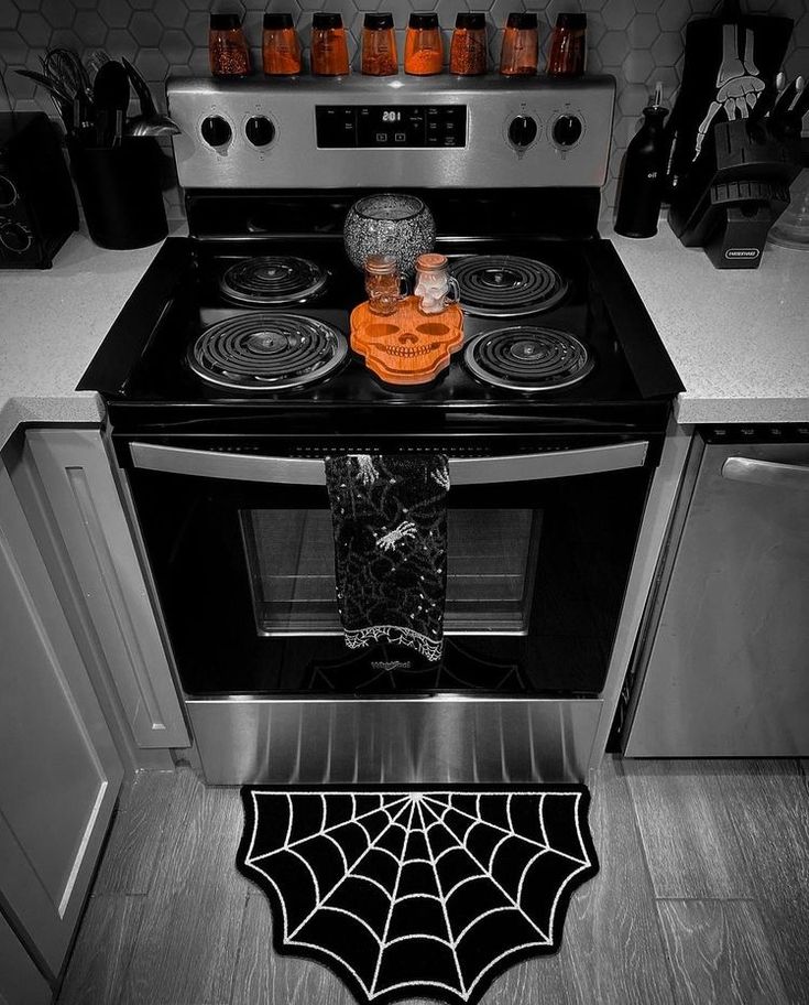 a black and white photo of a kitchen with a spider web rug on the stove