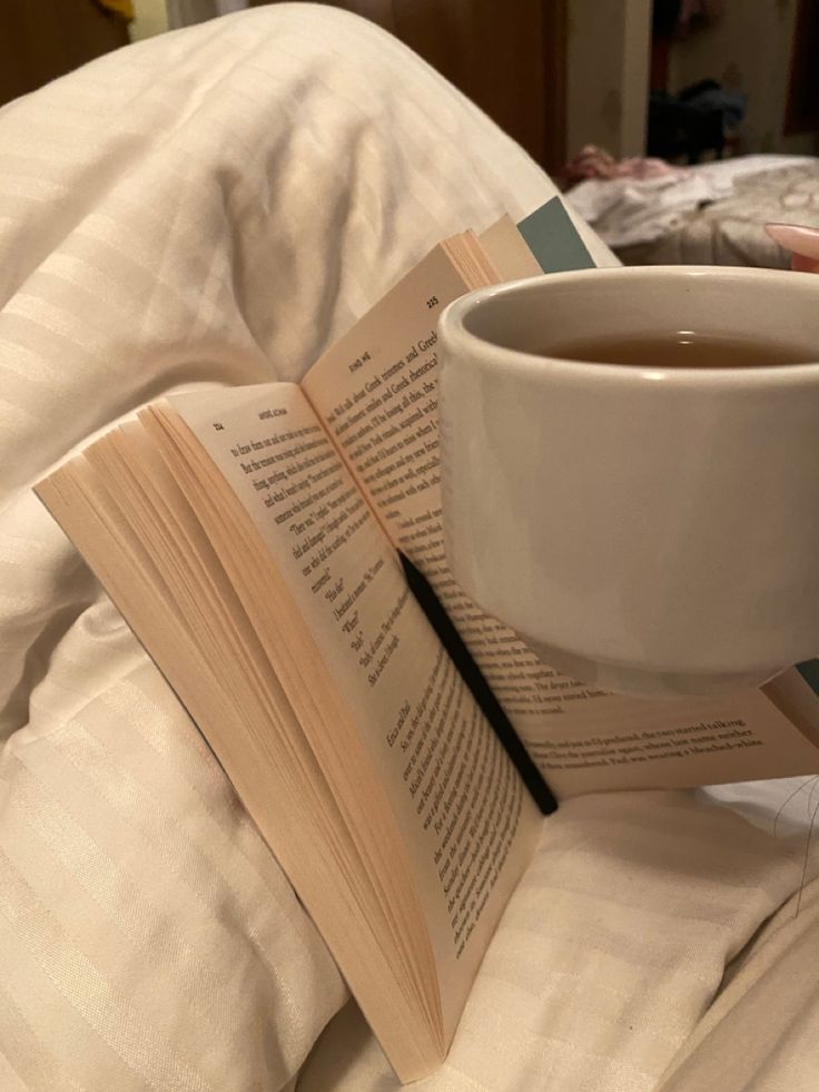 a cup of tea and an open book on a bed