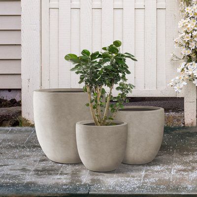 three cement planters sitting next to each other on a concrete slab in front of a white house