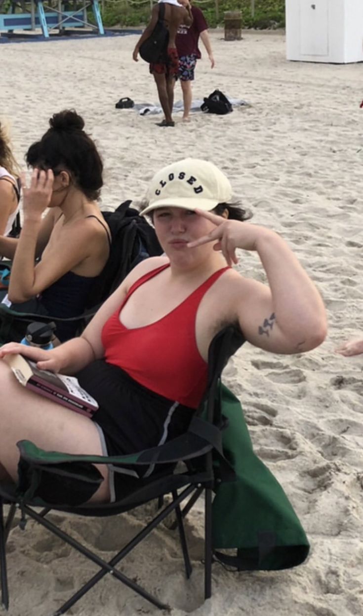 a group of people sitting on top of a beach next to each other in lawn chairs