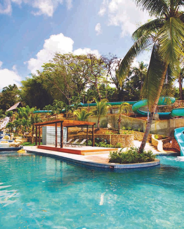 an outdoor swimming pool with slides and palm trees