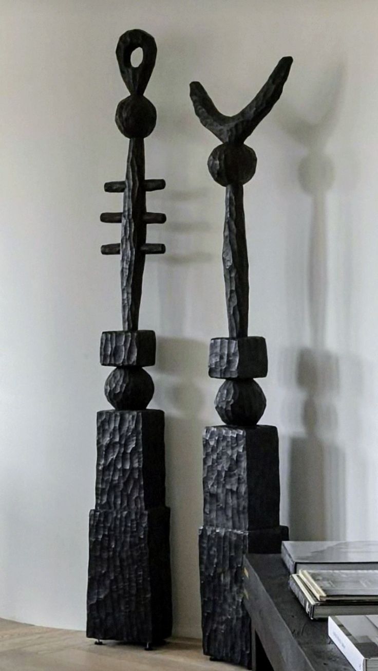 two black sculptures sitting on top of a wooden table