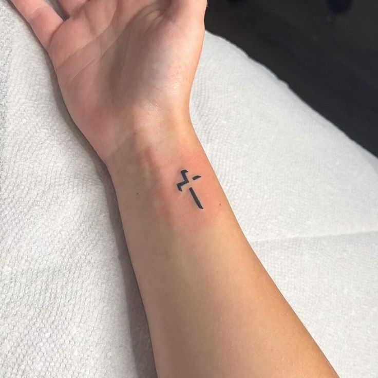 a woman's arm with a cross tattoo on it