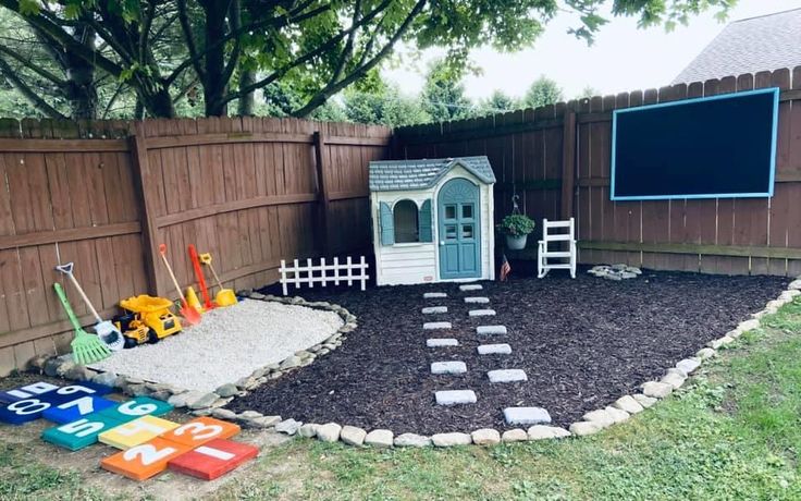 a backyard with a little house in the middle and toys on the ground next to it