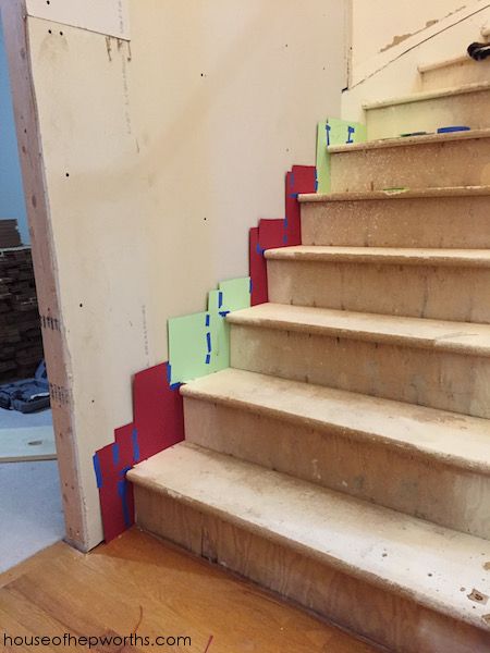 a set of stairs with red and green tape on the bottom, next to an unfinished wall