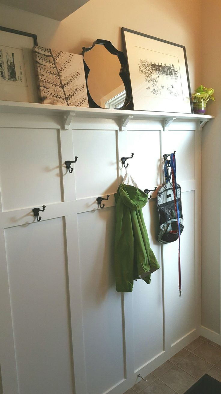 a coat rack with two coats hanging from it's hooks and some pictures on the wall