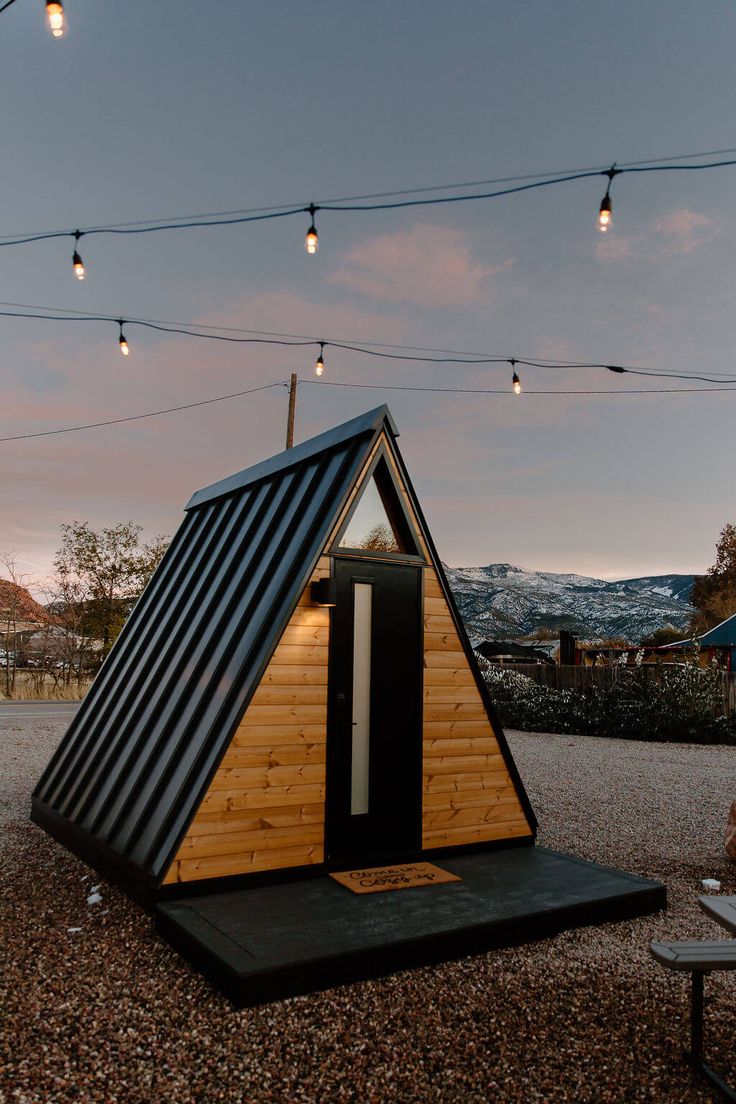 a small wooden structure with lights hanging from it's sides and the door open