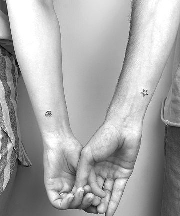 two people holding hands with small stars on their wrist tattooing one another's hand