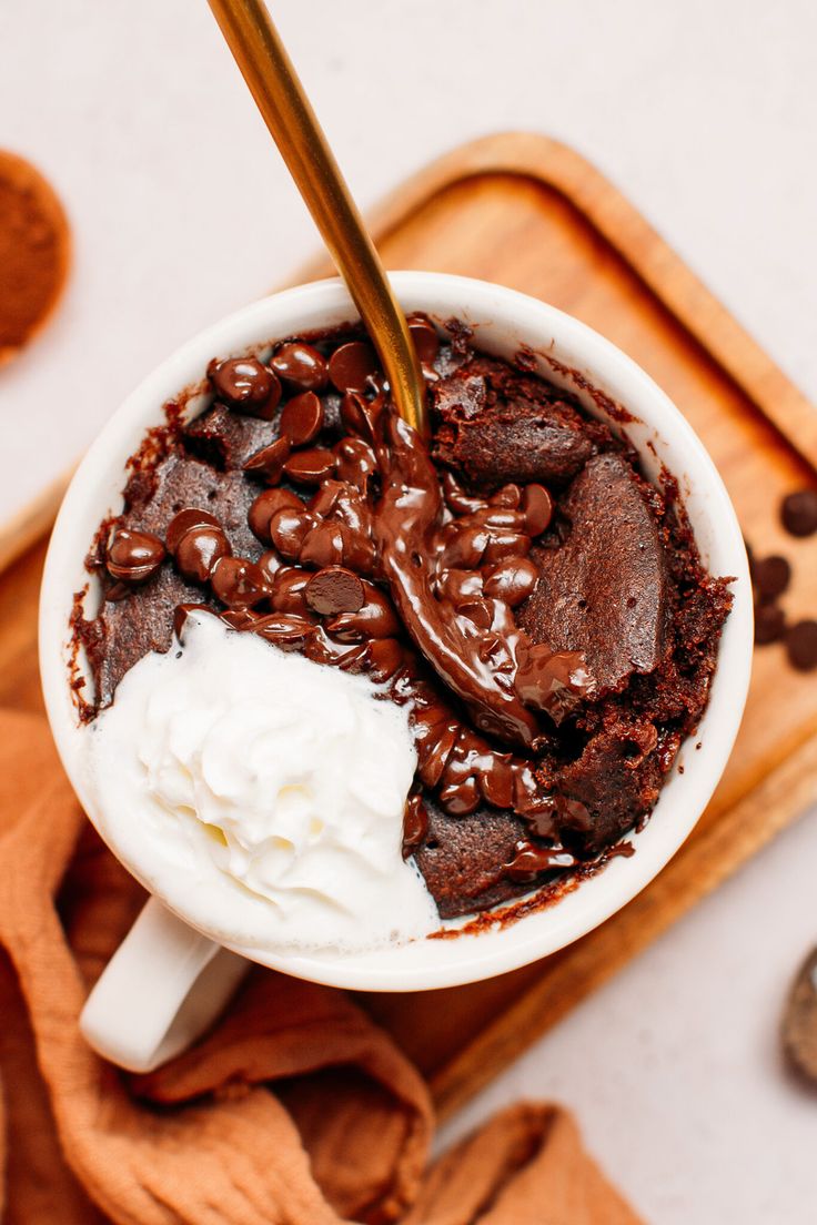 a cup filled with chocolate pudding and whipped cream on top of a wooden tray next to cookies