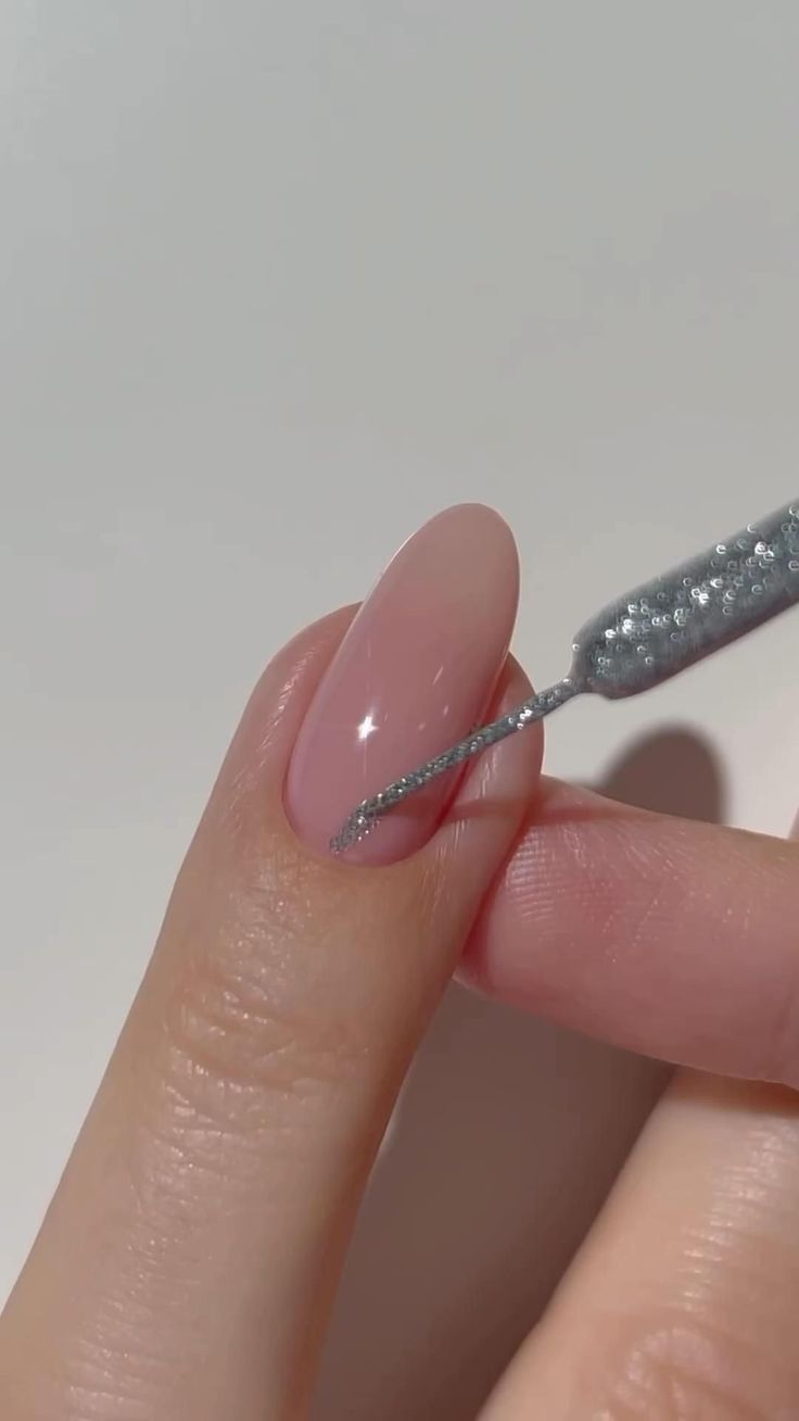 a woman's hand holding a small toothbrush with pink and silver glitter on it