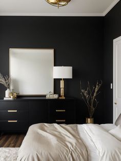 a bedroom with black walls, white bedding and gold accents on the nightstands