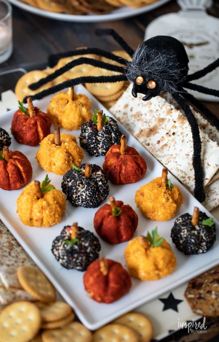 halloween treats are arranged on a plate with spider decorations and crackers in the shape of pumpkins