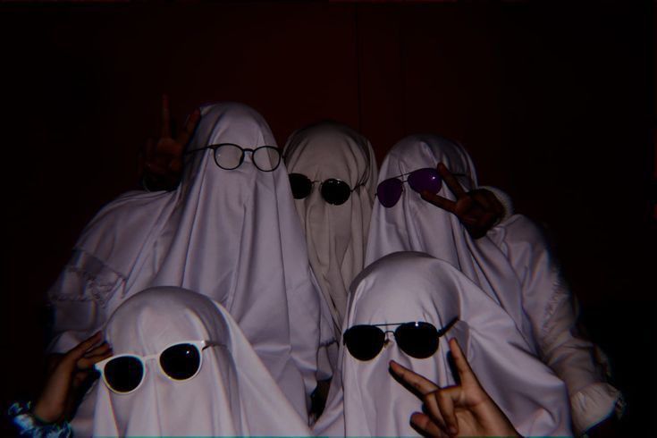 four people in white ghost costumes with sunglasses and pointing fingers at the camera while wearing glasses