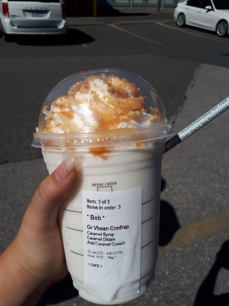 a person holding up a plastic cup with food in it and a straw sticking out of the top