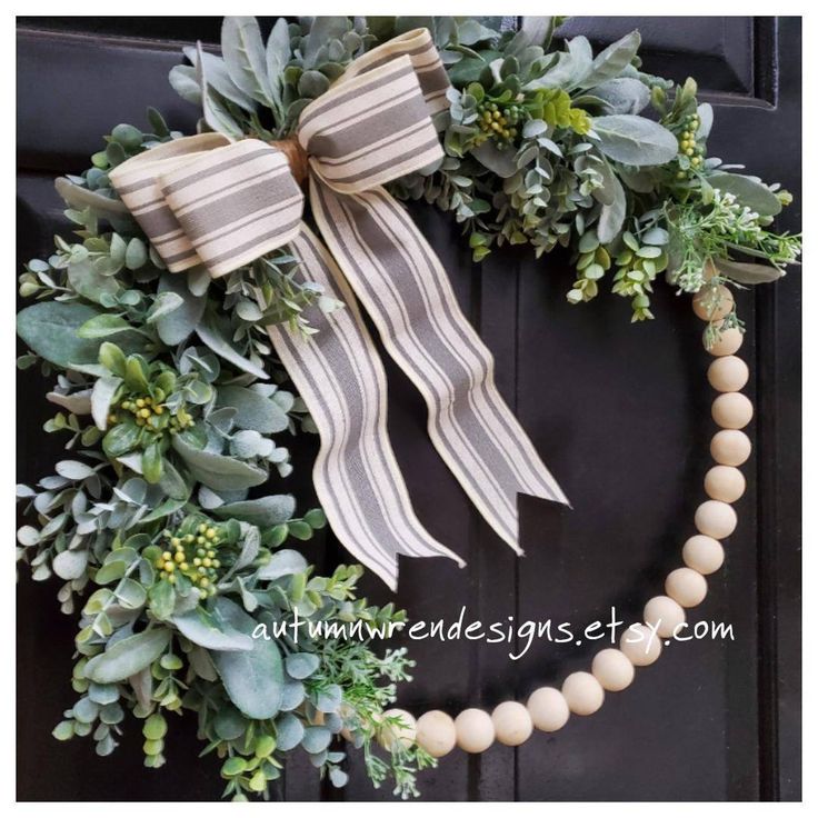 a wreath is hanging on the front door with greenery around it and a beaded necklace