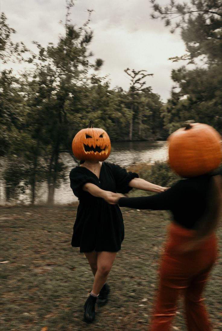 two people dressed up as jack - o'- lantern and one is holding hands