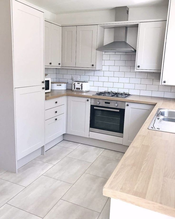 an empty kitchen with white cabinets and tile flooring