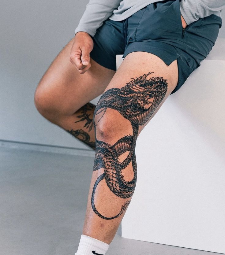 a man with tattoos on his legs and knee