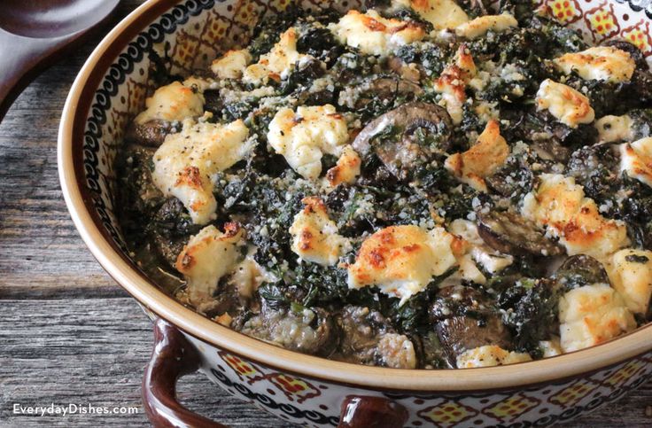 a casserole dish with spinach and cheese in a bowl on a wooden table