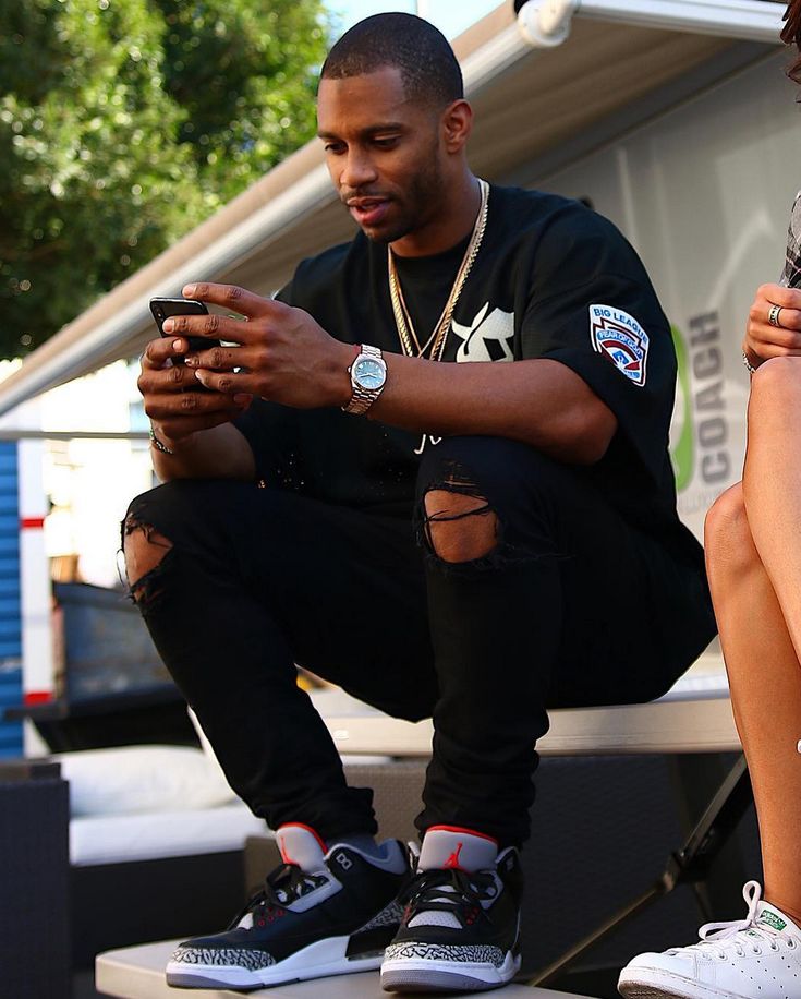 a man sitting on top of a bench while looking at his cell phone in front of him