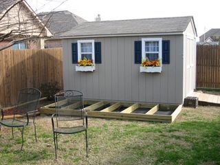 a backyard with a shed, table and chairs in it next to a fenced yard