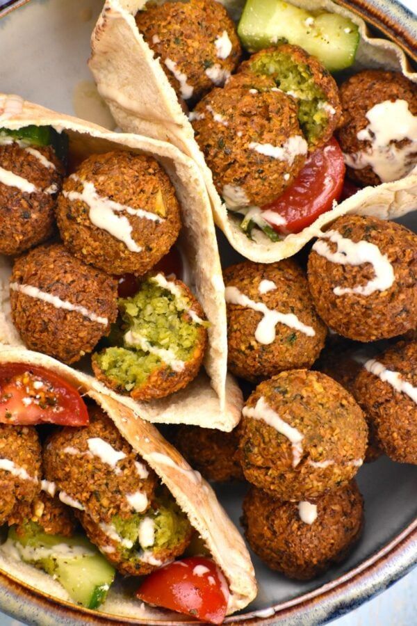 some falafes are on a plate with tomatoes and cucumbers