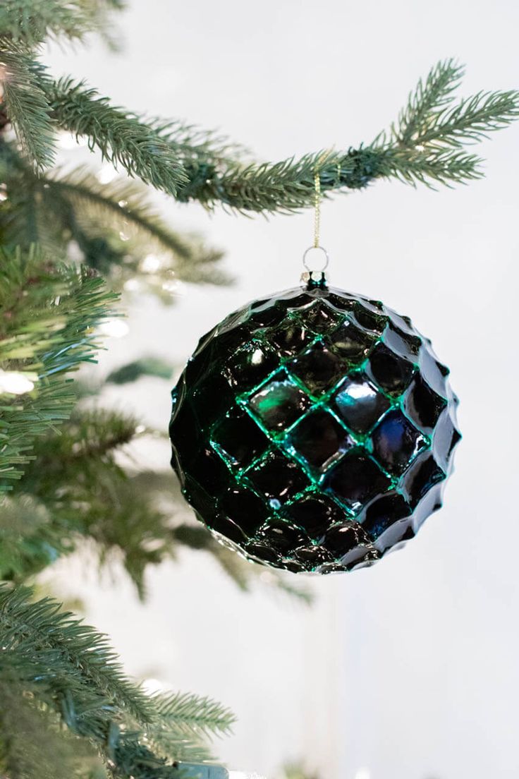 a black ornament hanging from a christmas tree with green lights on it's branches