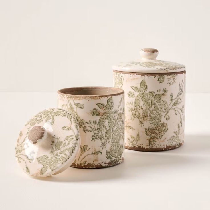 three ceramic containers with lids and designs on them