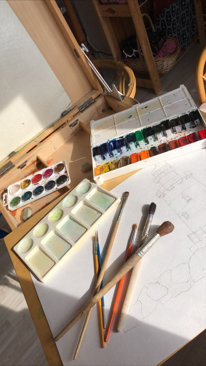 an artist's desk with paints, brushes and watercolors