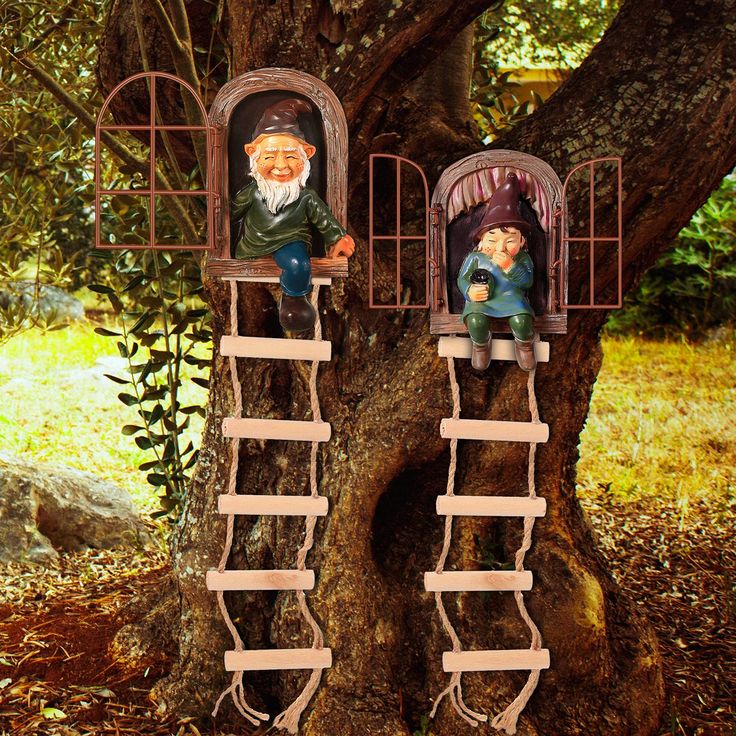 two gnomes are sitting on top of ladders next to a tree