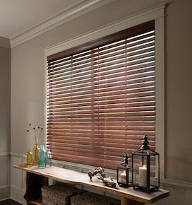 a table with some vases and candles on it next to a window covered in blinds