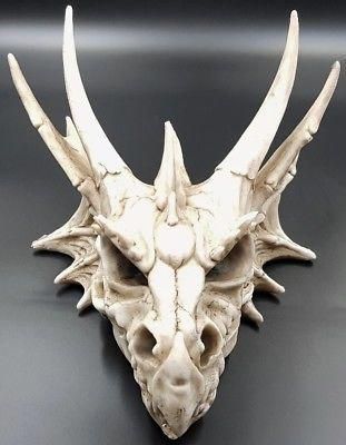 a white mask with large horns is on a black surface and it looks like an animal's head