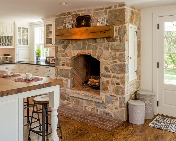 a stone fireplace in the middle of a kitchen