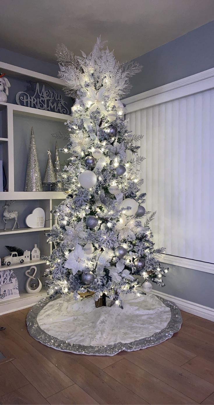 a white christmas tree with silver ornaments and lights