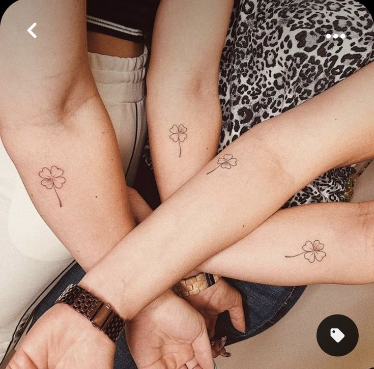 two people with matching tattoos on their arms sitting next to each other and holding hands