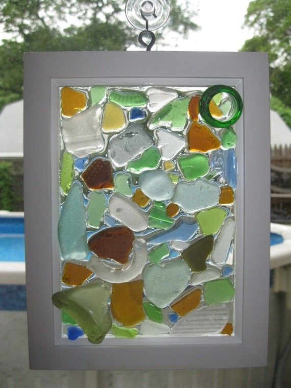 a stained glass piece hanging from a hook in front of a swimming pool with trees