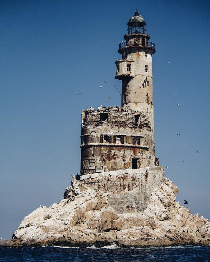 an old lighthouse on top of a rock in the ocean