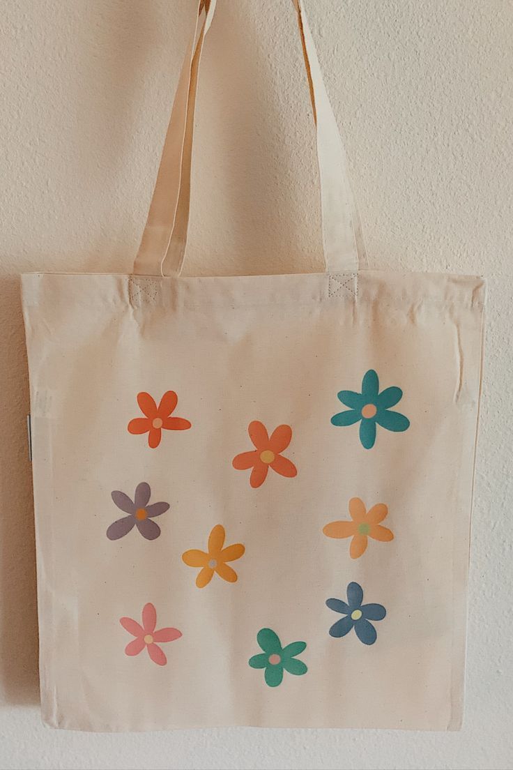 a white bag with flowers painted on it hanging from the wall next to a door