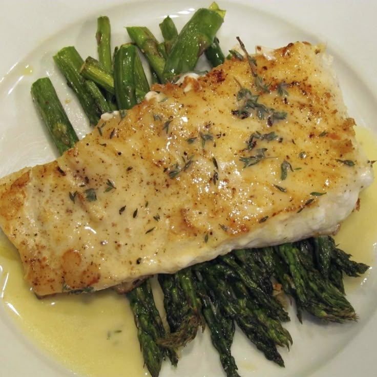 a white plate topped with fish and asparagus