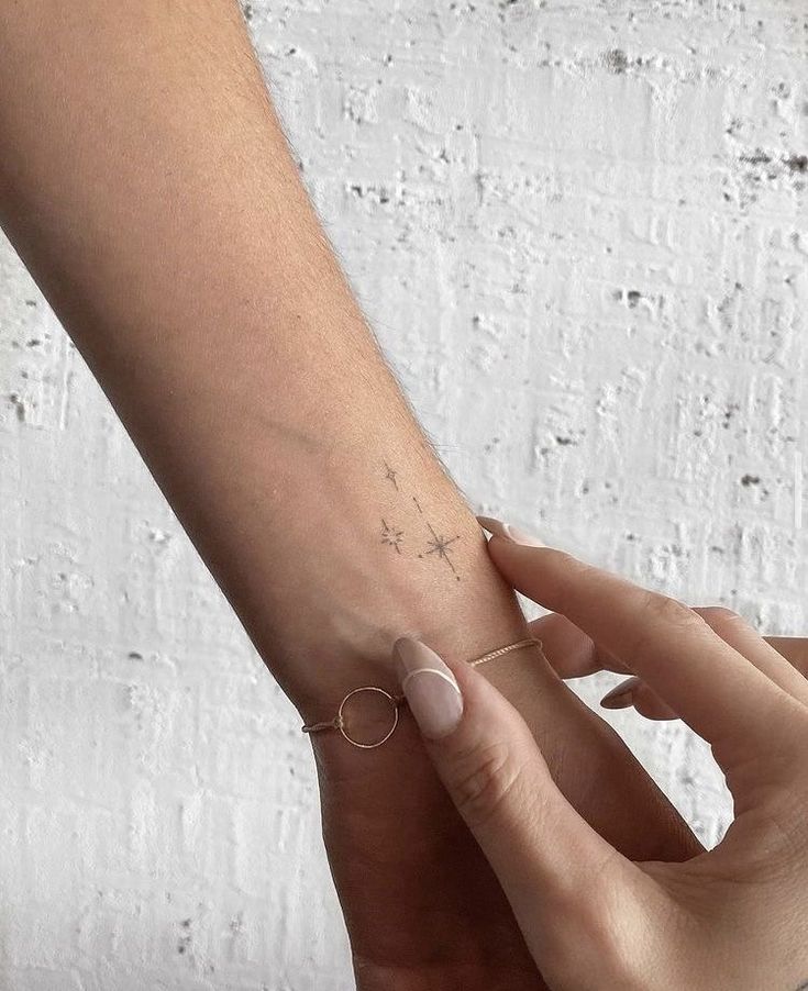 a woman's arm with a small star tattoo on the left side of her wrist