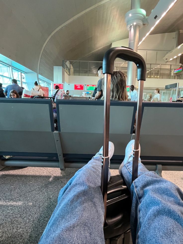 someone is sitting in an airport with their feet propped up on the luggage carousels