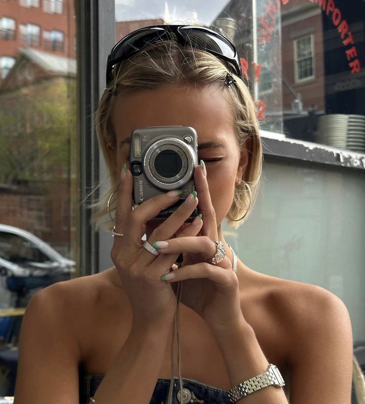 a woman taking a selfie in front of a window with her camera up to her face