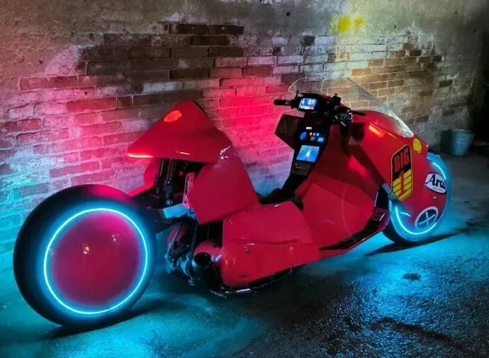 a red motorcycle parked next to a brick wall with neon lights on it's side