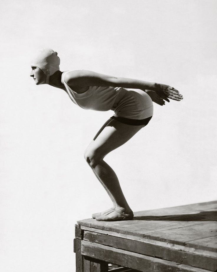 an old black and white photo of a woman doing yoga on a wooden platform with her hands in the air