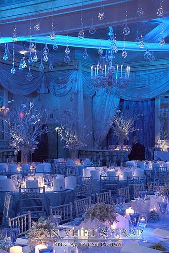 an image of a banquet room set up for a formal function with blue lighting and chandeliers